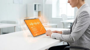 Une personne utilisant une tablette affichant des ondes sonores et des données numériques dans un bureau lumineux.